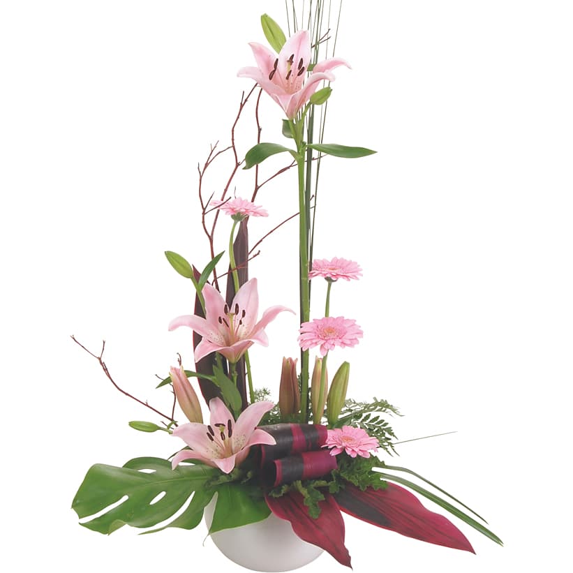 A modern pink ceramic container with lilium, mini gerberas, twigs, and tropical foliage for a chic look.