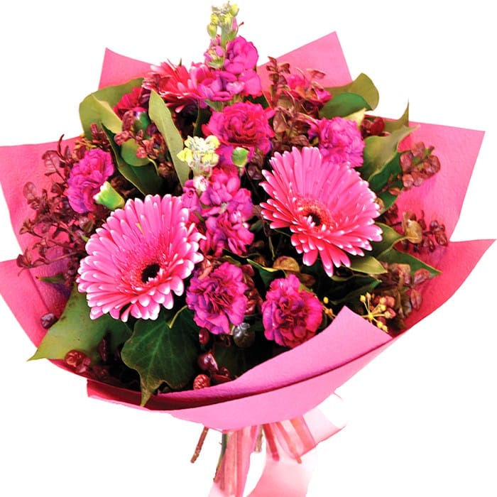 A soft pink bouquet of gerberas, carnations, and stock with beech and greenery for a charming look.