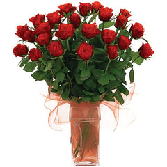 A clear glass vase holding 24 long-stem red roses, accented with cord and netting for a luxurious floral display.
