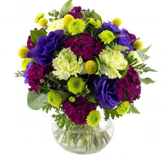 A vibrant bouquet of purple lisianthus, green carnations, pink sweet william, billy buttons, and greenery.