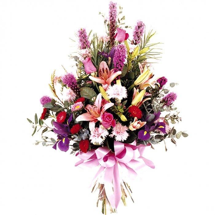 A vibrant sheath bouquet of pink and purple liatris, roses, lilies, iris, carnations, and mini gerberas with greenery.