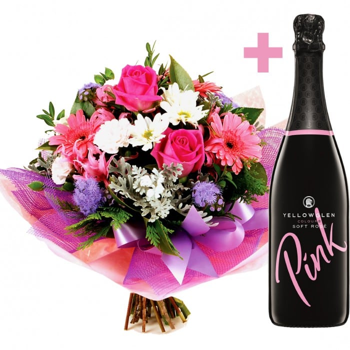 A vibrant pink and white bouquet of gerberas, roses, ageratum, and spray carnations with a 750ml bottle of Pink by YellowGlen.
