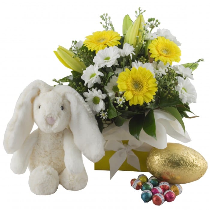 Easter Delight flower arrangement with eggs and bunny: Yellow and white Easter box arrangement with lilies, gerberas, a plush toy, and chocolate eggs.